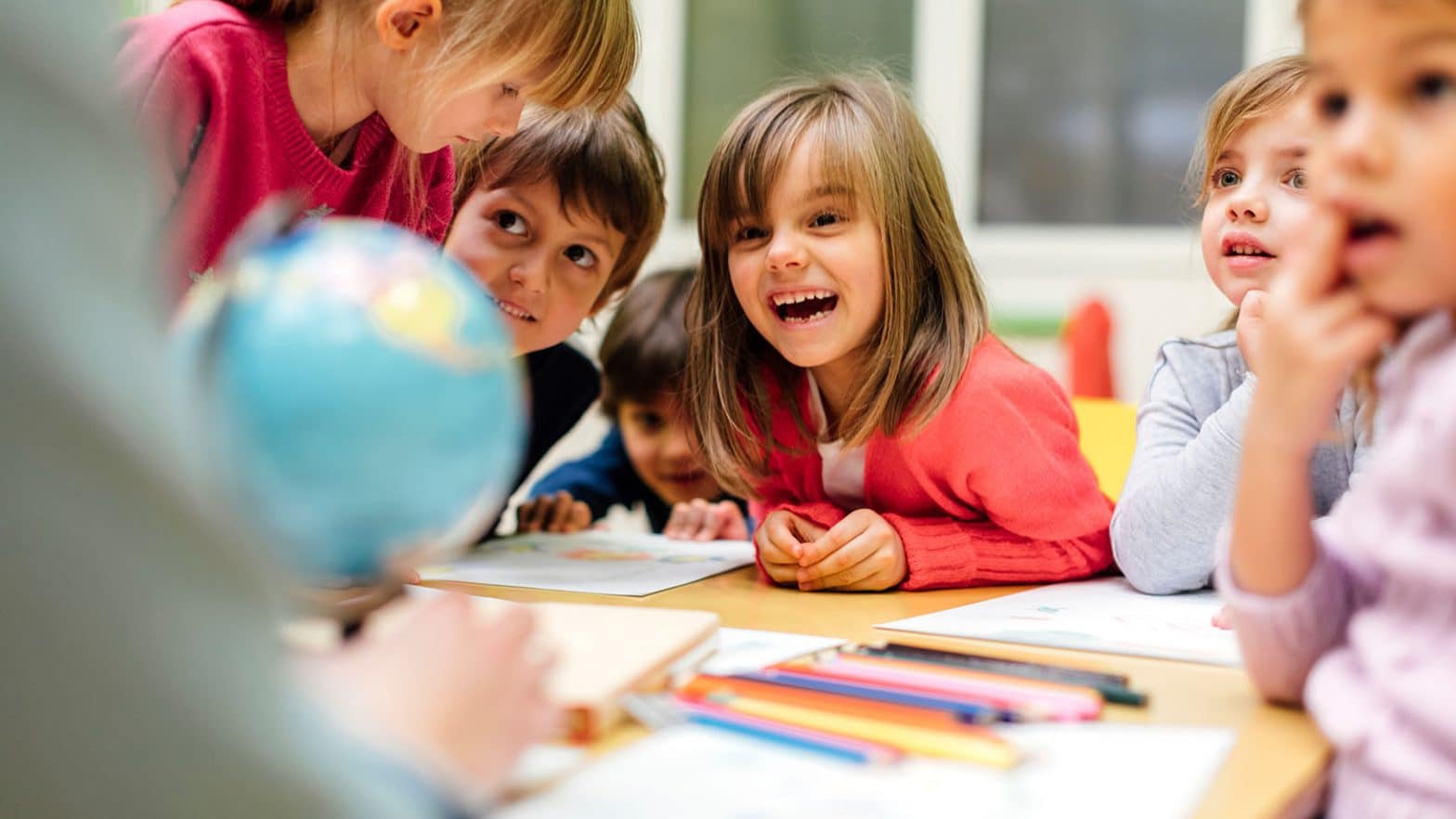 Preschool teacher and children using globe.