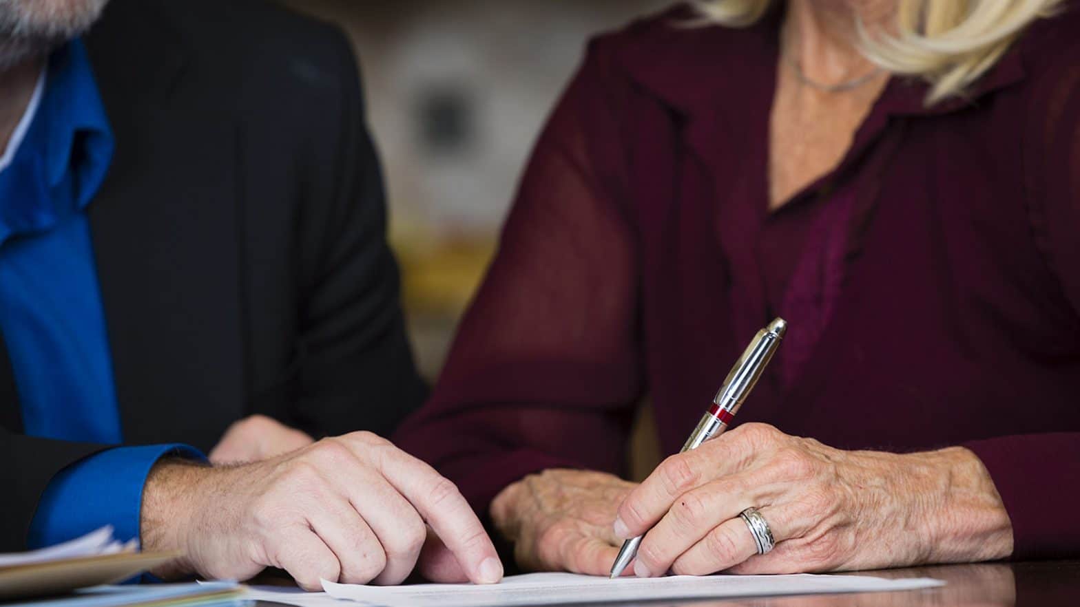 A senior citizen signing a document.