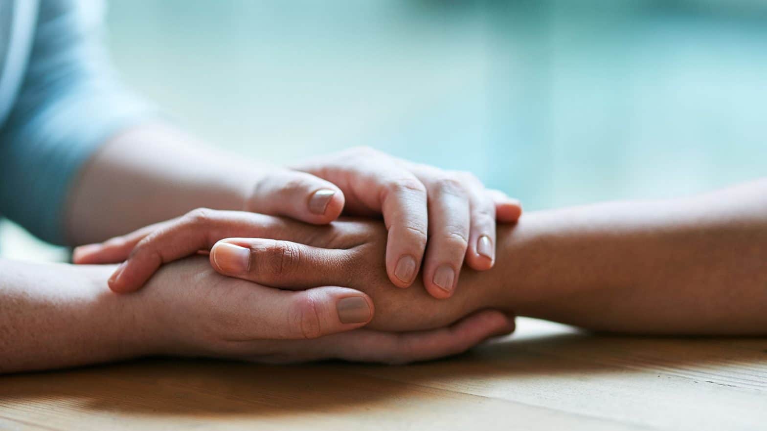 A pair of hands holding another's hand in a comforting gesture