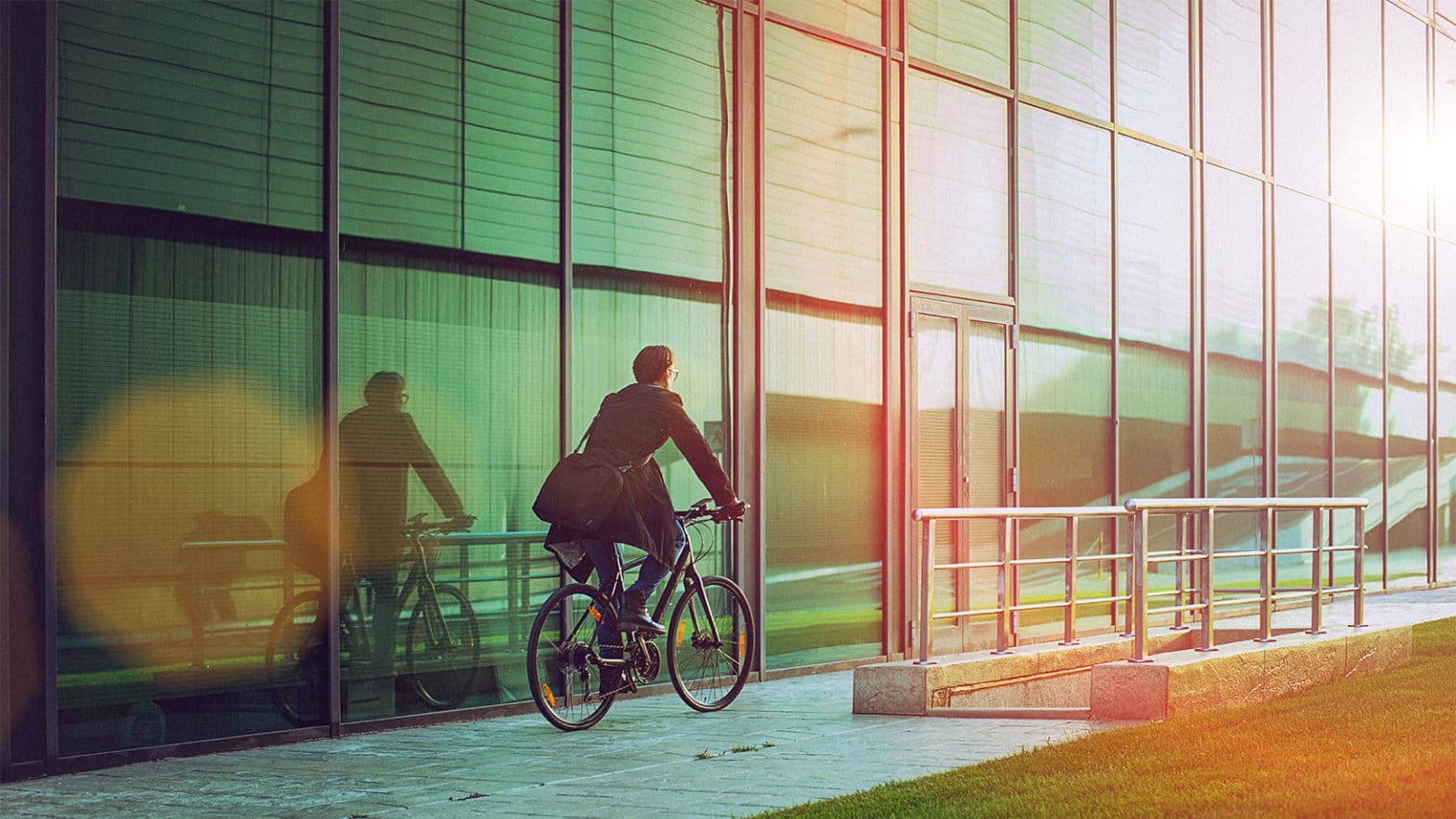 Man cycling past glass-fronted office block